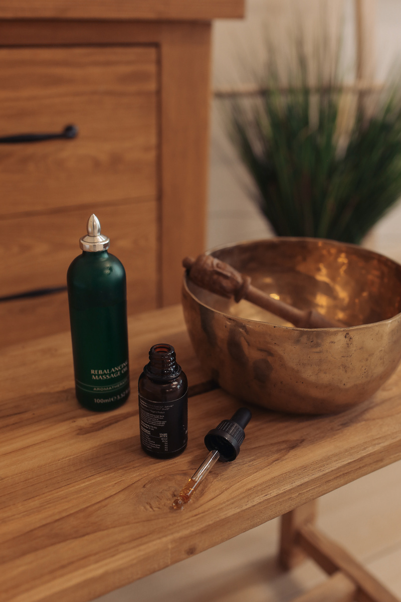 Massage Oil and Singing Bowl on Wooden Table